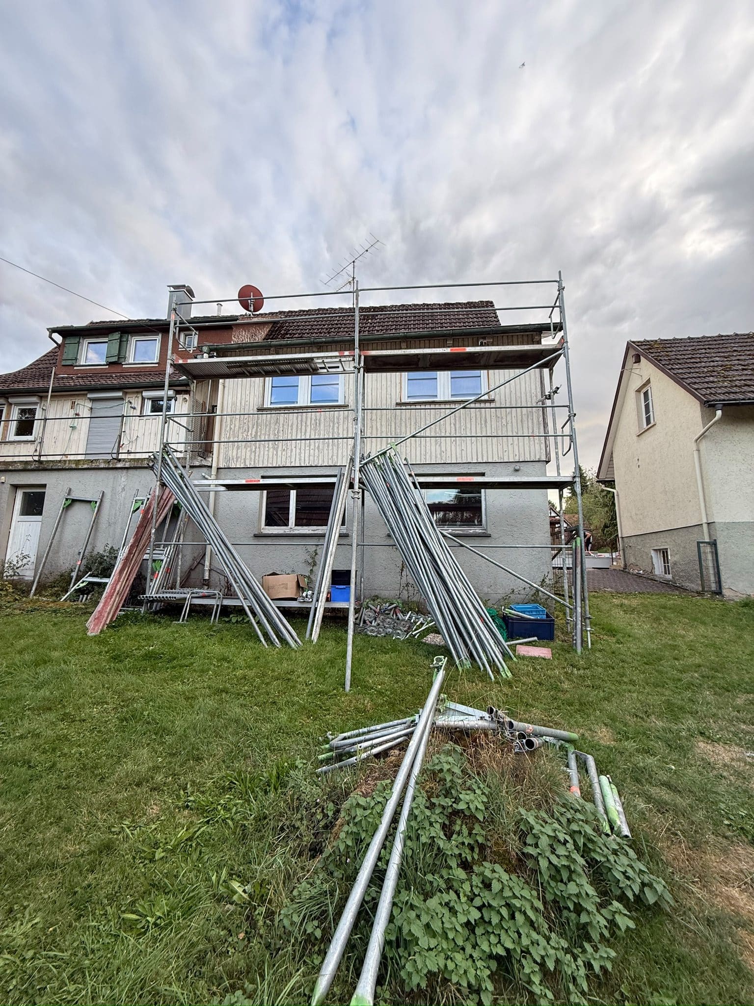Gerüst im Aufbau an einem zweistöckigen Wohnhaus